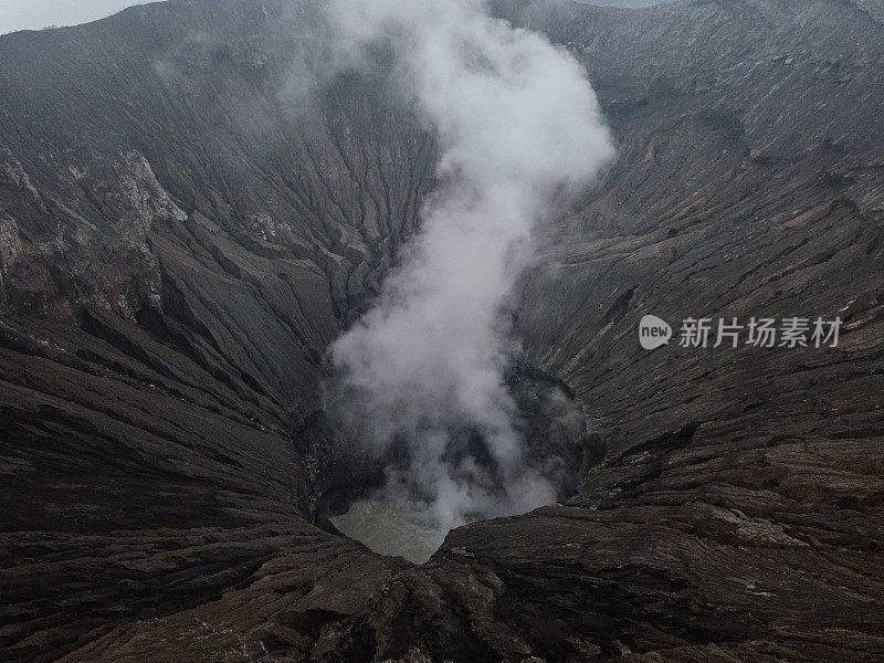 无人机鸟瞰图的Bromo火山口边缘与蒸汽在Bromo山国家公园在Cemoro Lawang村-东爪哇，印度尼西亚，亚洲。旅游目的地冒险的自然概念